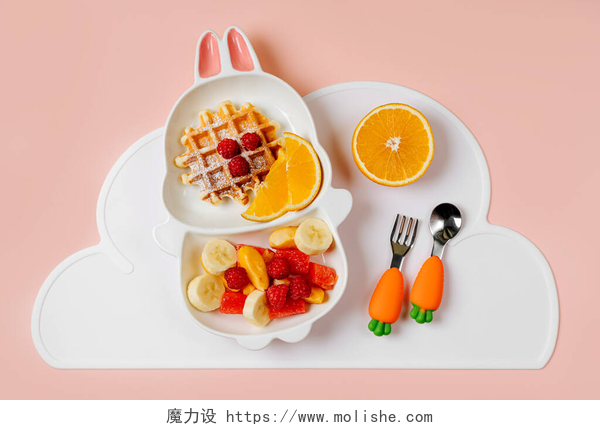 粉色桌子上的婴儿水果儿童早餐。用松饼和水果做成的兔子形的小盘子.给孩子们的食物建议.